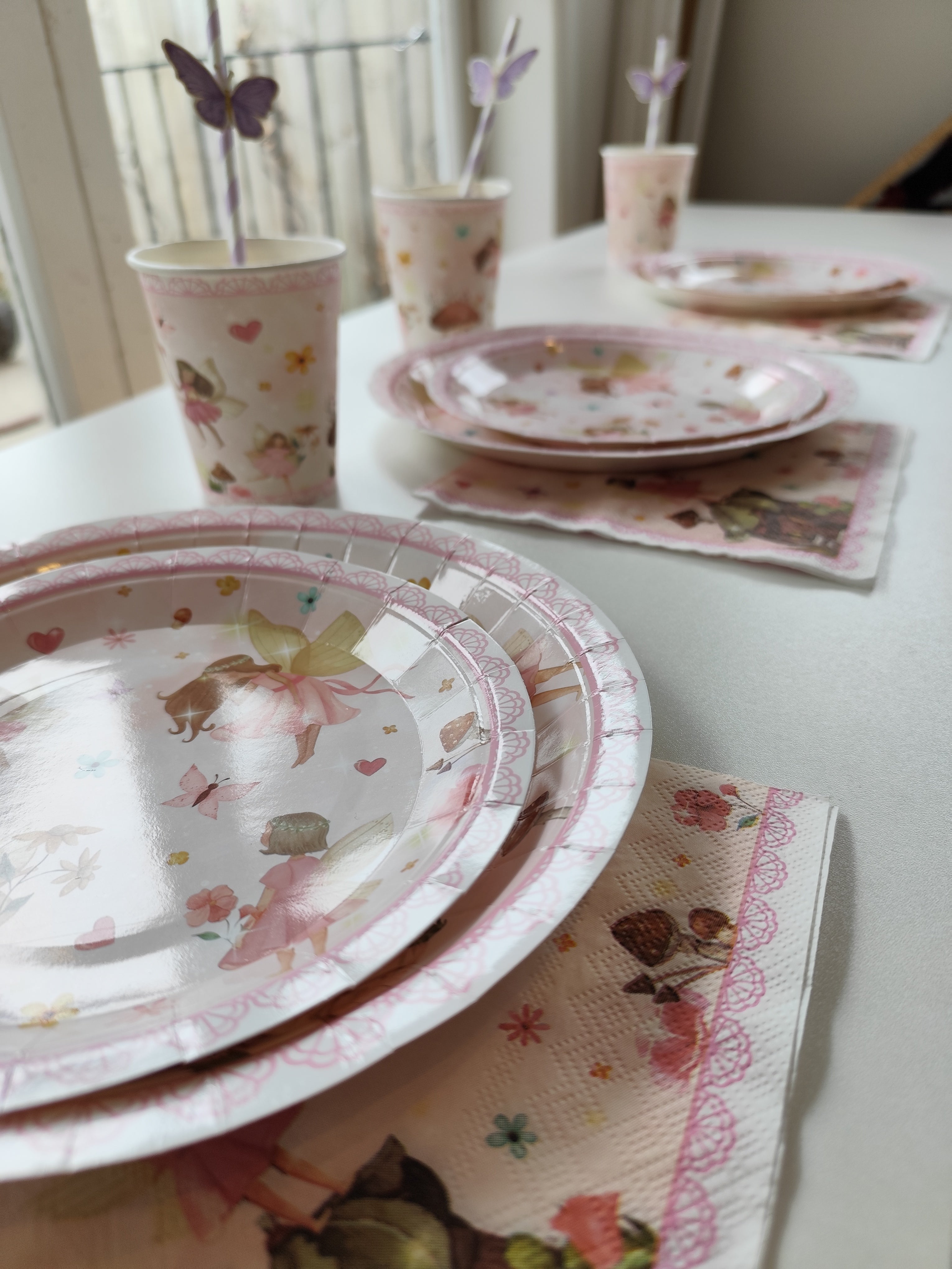 Image of fairy themed tableware and butterfly straws set up for a party on a table. 